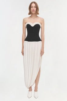 Strapless dress with black fitted bodice, white beaded neckline trim, and cream pleated asymmetrical skirt.