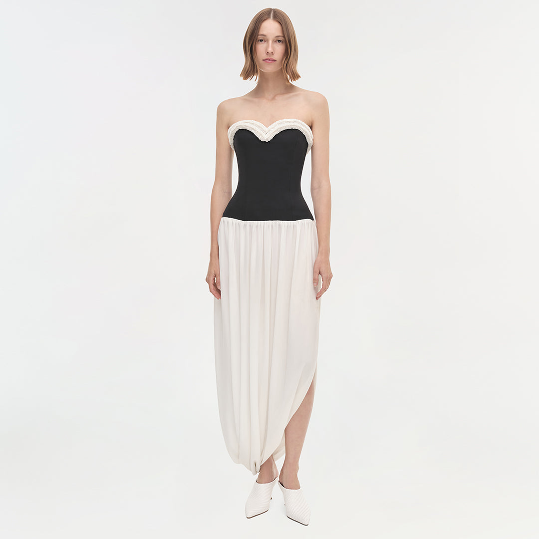 Strapless dress with black sweetheart neckline bodice and white pleated asymmetrical skirt.