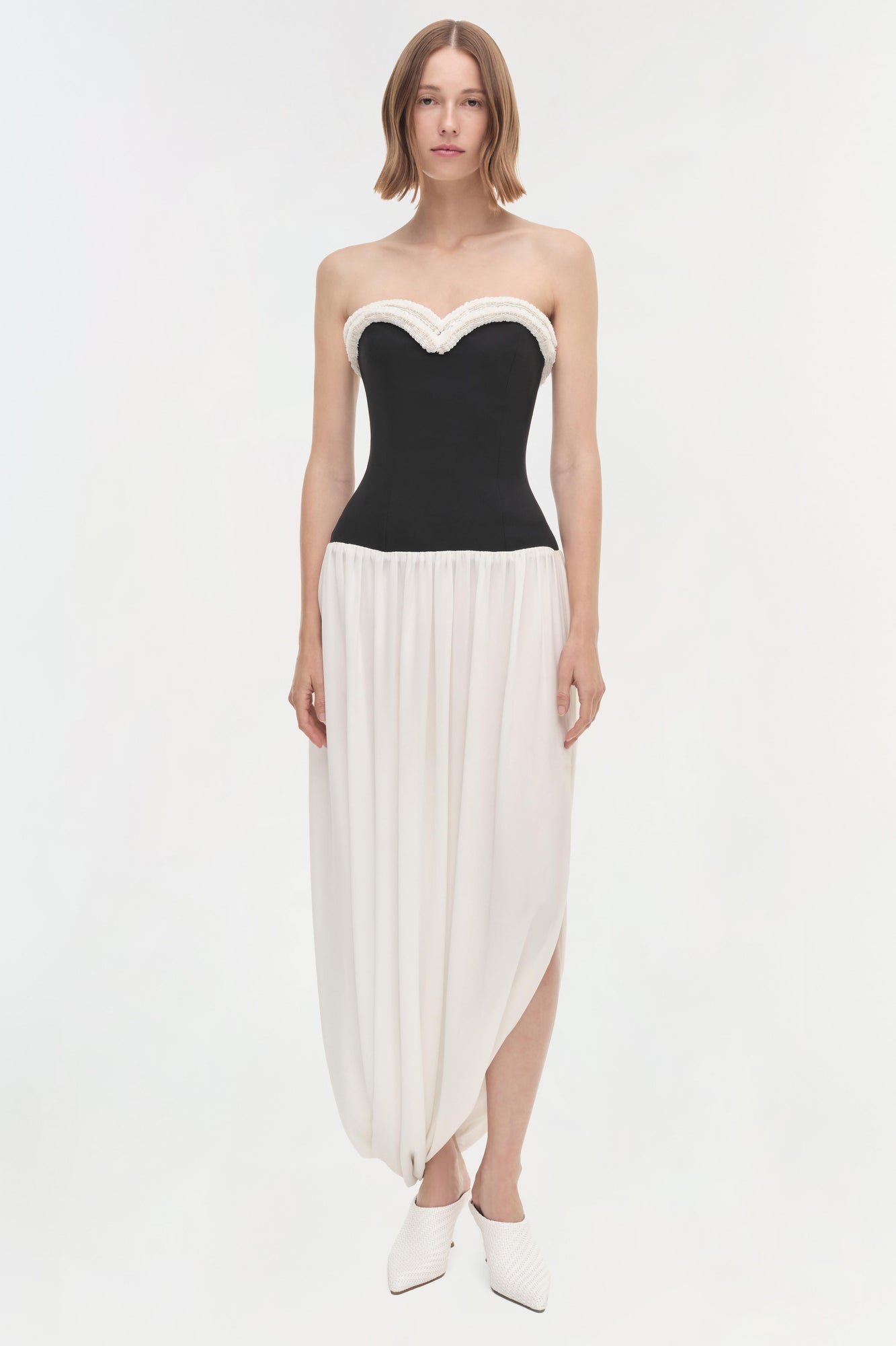 Black and white strapless dress with sweetheart neckline, fitted bodice, and asymmetrical draped skirt.