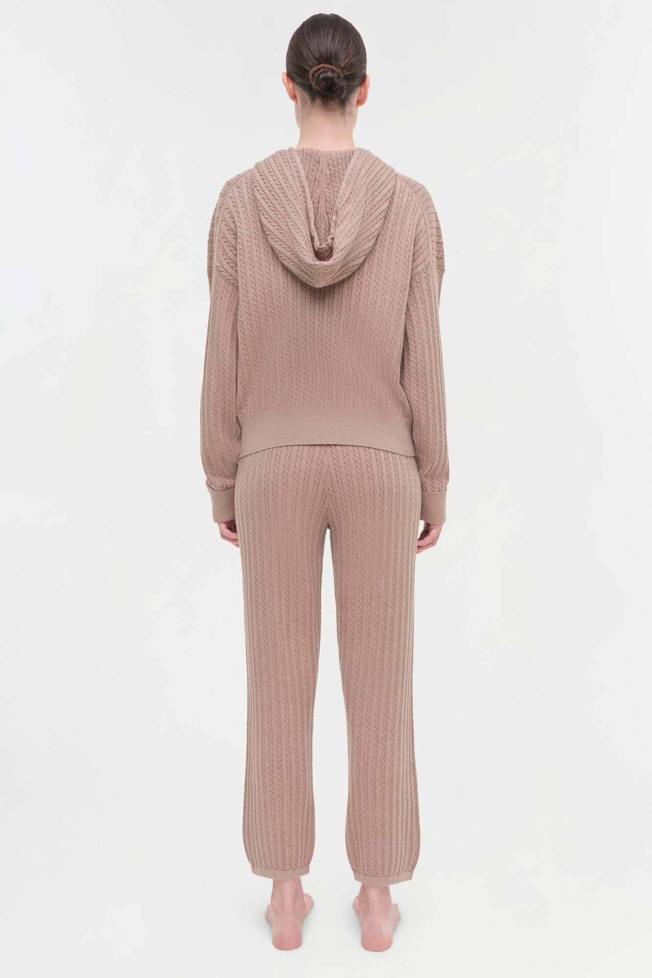 Beige cable knit hoodie and matching jogger pants on model, shown from back view.