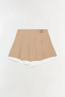 Beige pleated skort with white shorts underneath and two buckle details at the waistband.