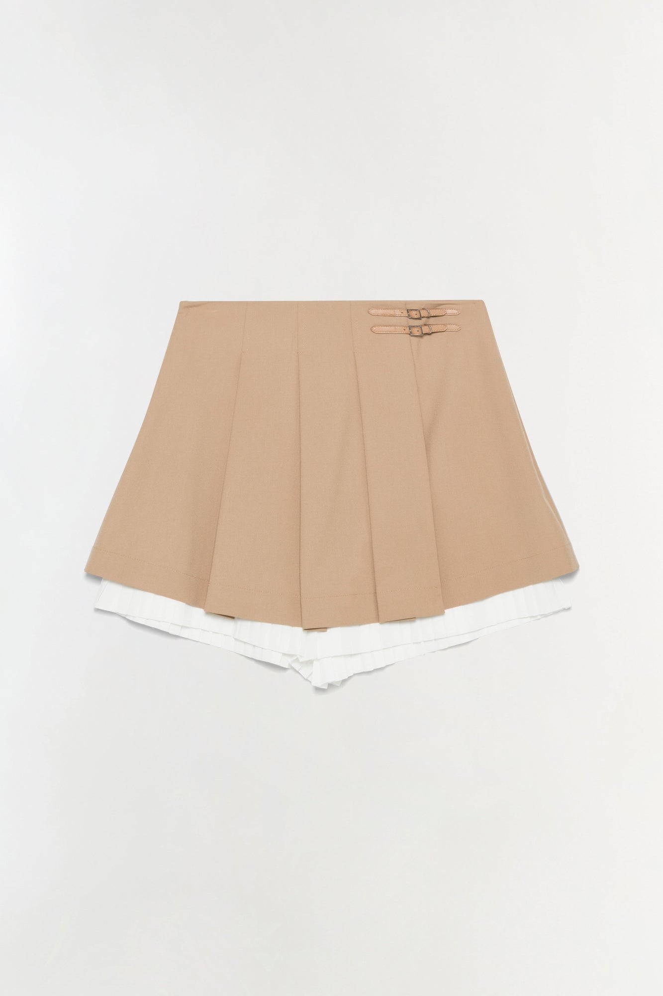 Beige pleated skort with white shorts underneath and two buckle details at the waistband.