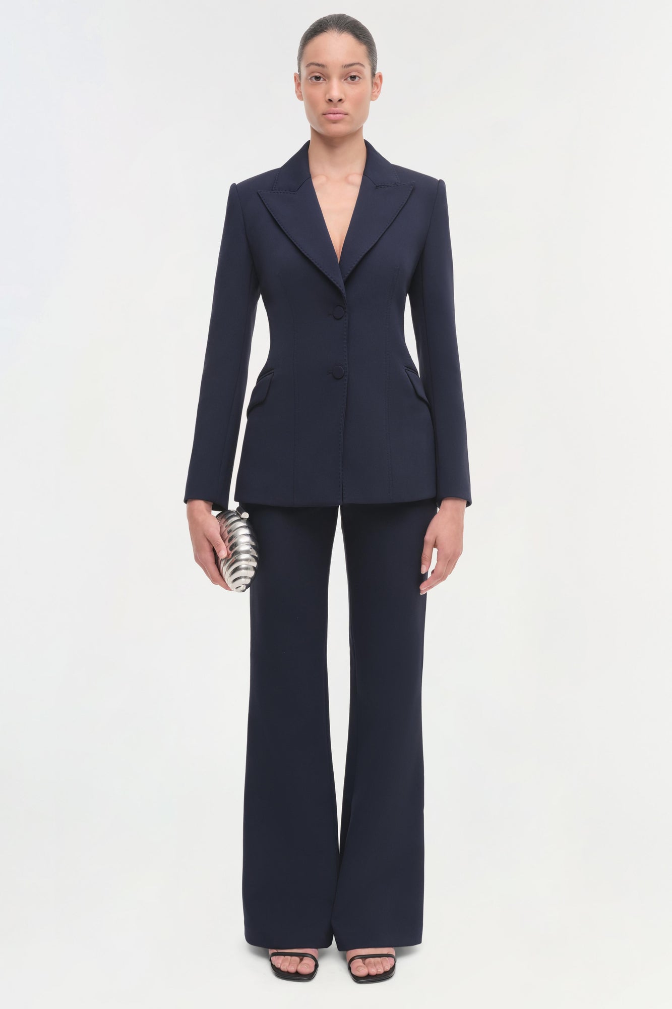 Navy blazer with notch lapels, button closure, and fitted waist, styled with matching trousers.