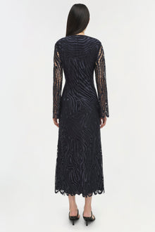Woman wearing a black lace midi dress with long patterned sleeves, shown from back view.