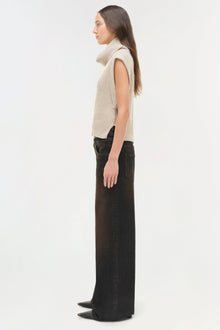 Cream ribbed sleeveless top with turtleneck collar worn with black wide-leg jeans.