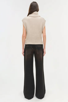 Cream ribbed sleeveless turtleneck top paired with black wide-leg jeans, shown on model from back view.