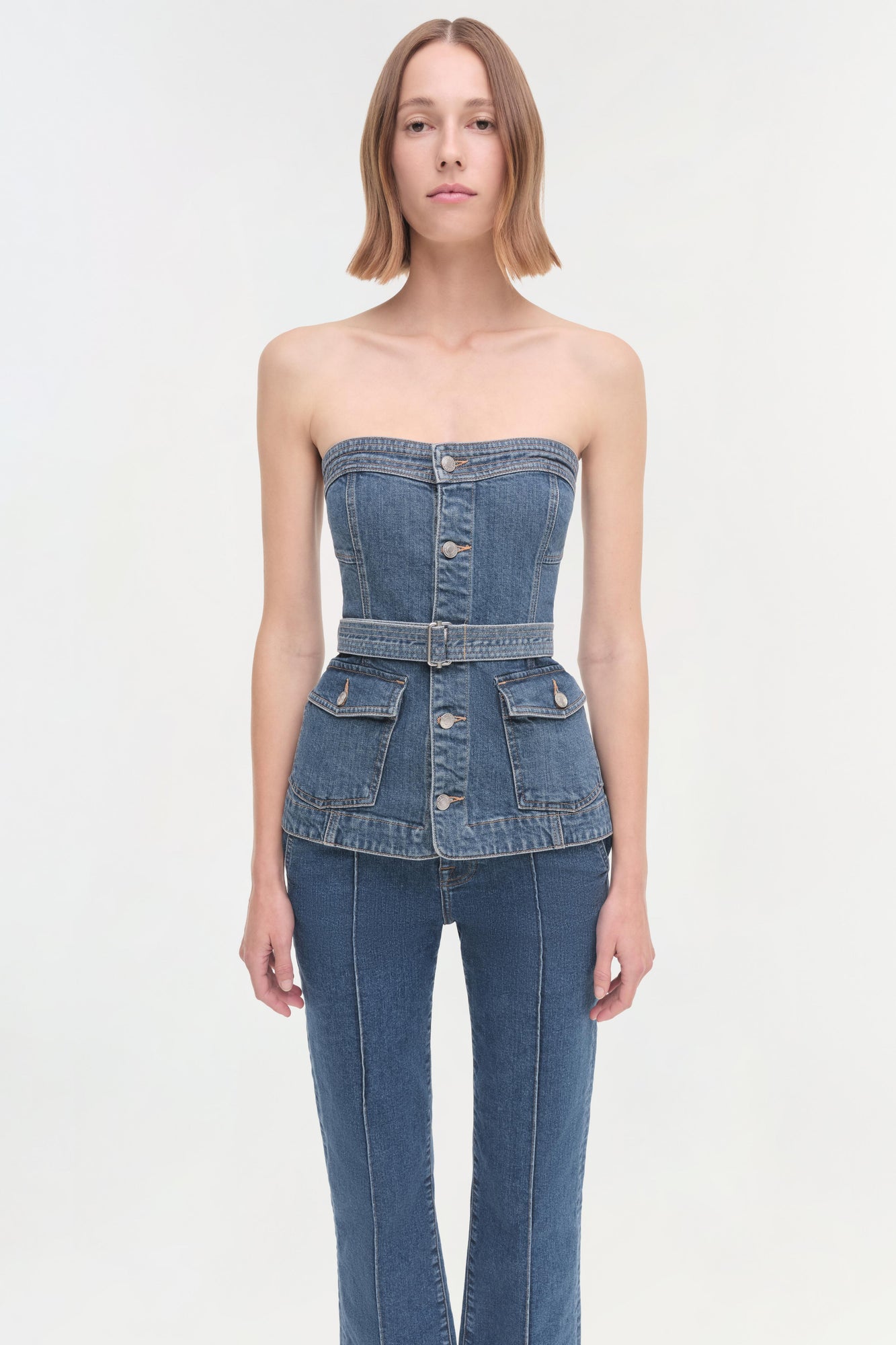 Woman wearing a strapless denim corset top with belt and matching jeans.