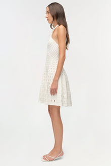 White sleeveless knit mini dress with eyelet pattern throughout, shown on model in side profile view.