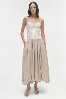 Sleeveless midi dress with cream polka dot top, beige pleated skirt, and thin straps.