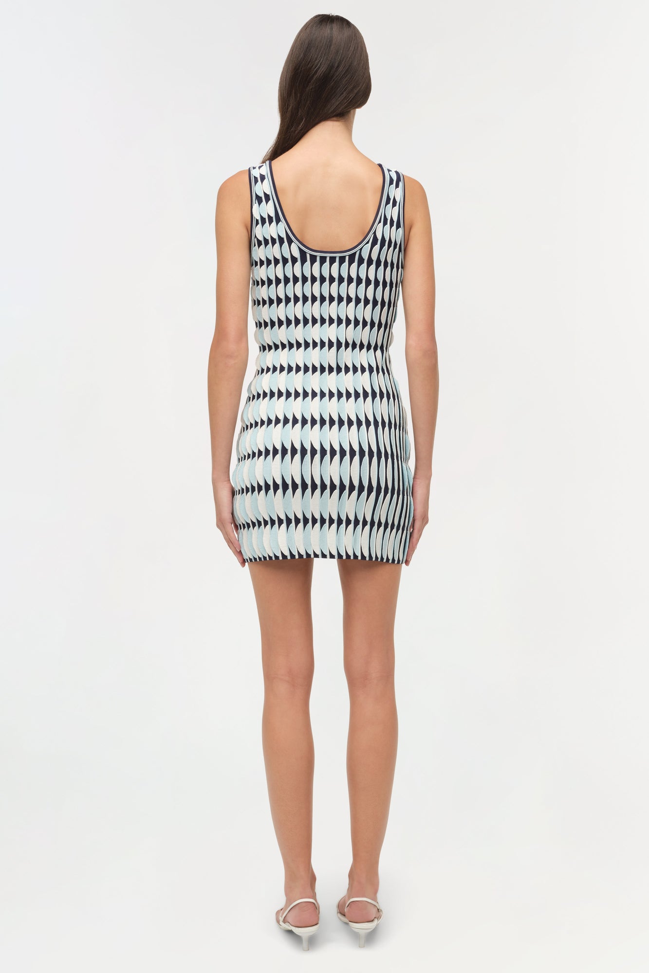 Sleeveless knit mini dress with black and white geometric arrow pattern and scalloped edges, shown from back.