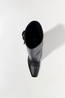 Black leather boot with fringe detail on the cuff, shown from above with lace-up closure at the top.