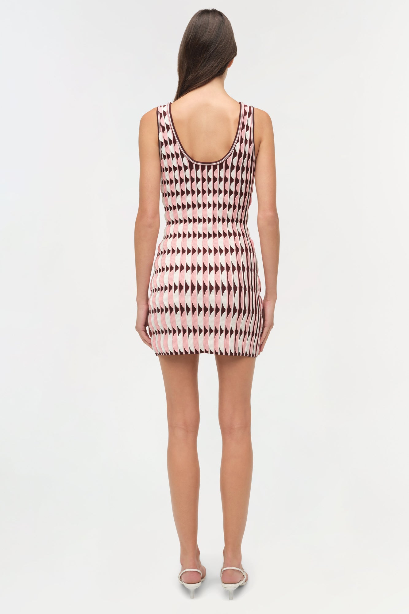 Sleeveless knit mini dress with scalloped geometric pattern in cream, burgundy, and pink worn with white slide sandals.