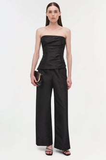 Black strapless bustier top with horizontal ruching paired with wide-leg black pants.