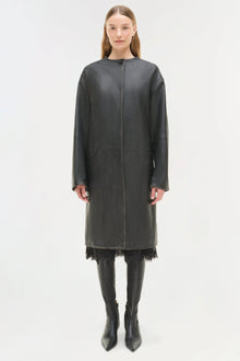 Woman wearing charcoal leather coat with lace trim hem, front zip closure, and long sleeves styled over black boots.