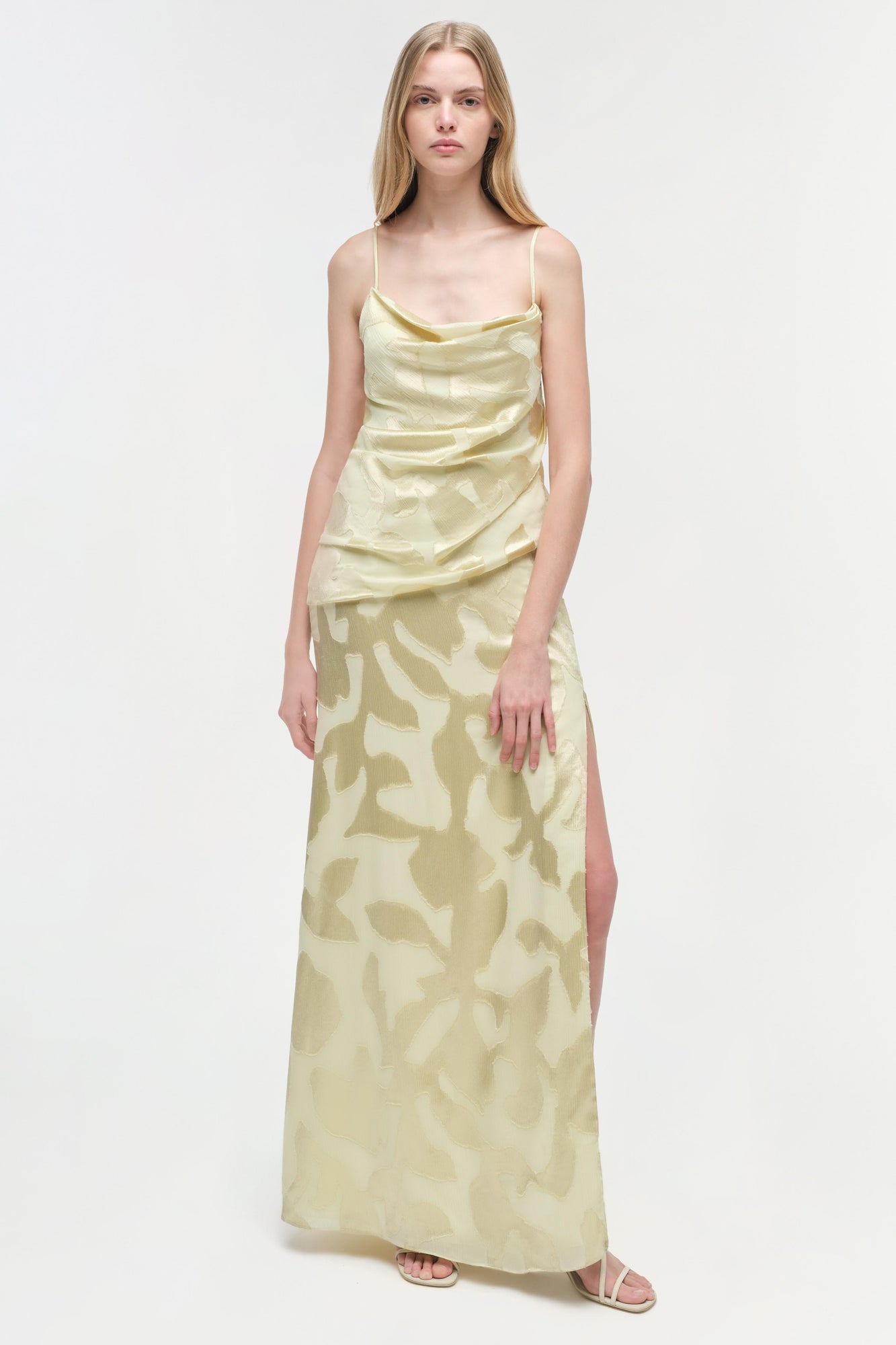 Cream-colored satin gown with abstract leaf print, cowl neckline, thin straps, ruched bodice, and side slit.