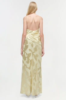 Cream-colored floor-length gown with abstract pattern, thin straps, and open back shown from behind on model.