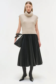 Black pleated midi skirt with high waist, styled with cream turtleneck sweater and black boots.