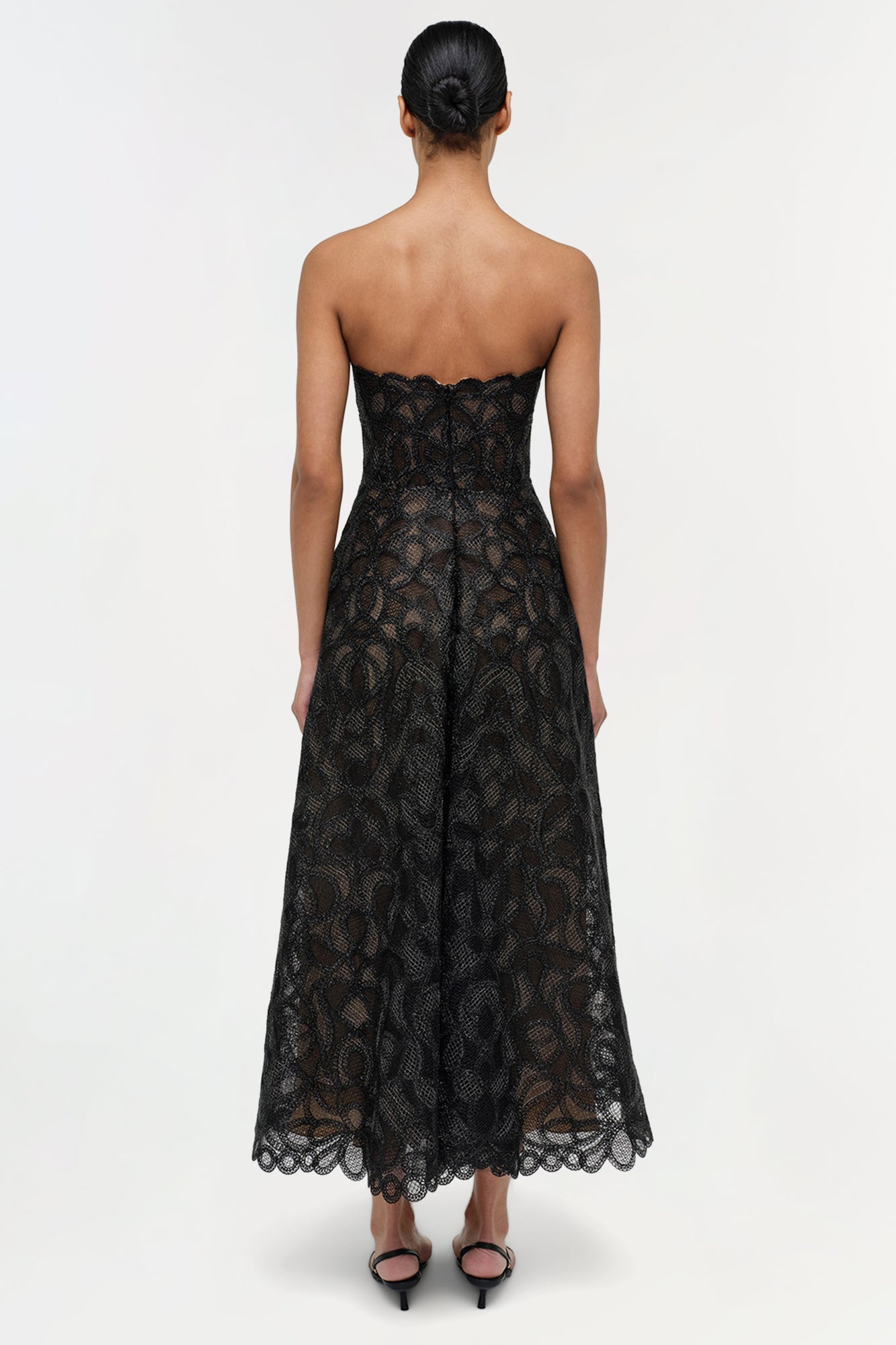 Black lace strapless midi dress with geometric patterning and scalloped hem, shown from back view.