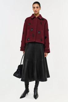 Black leather A-line midi skirt with center seam detail, worn with burgundy jacket.