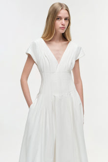 White cotton midi dress with short sleeves, V-neckline, ruched waist detail, and side pockets.