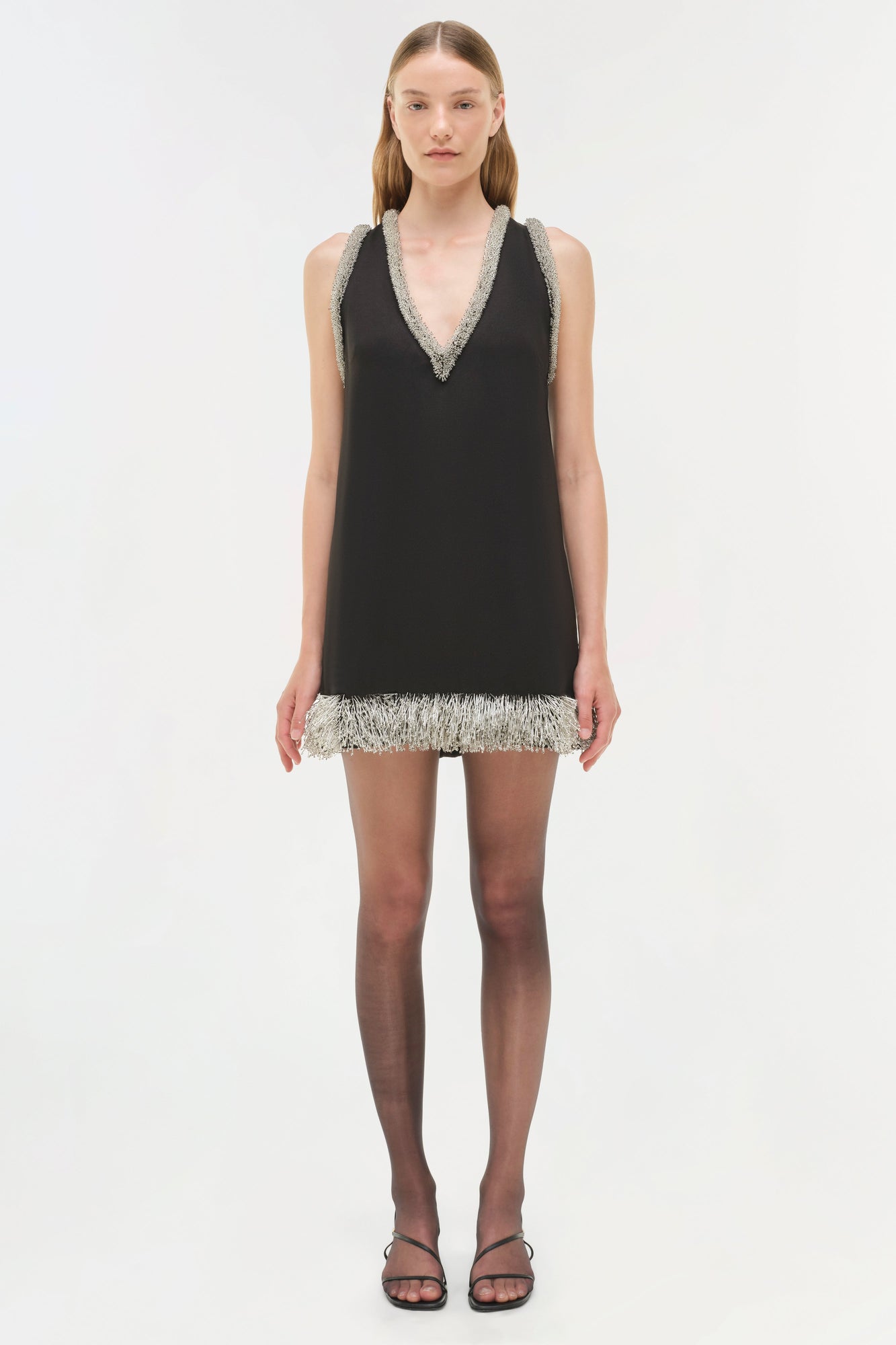 Black sleeveless mini dress with silver beaded V-neckline and fringe hem detail.