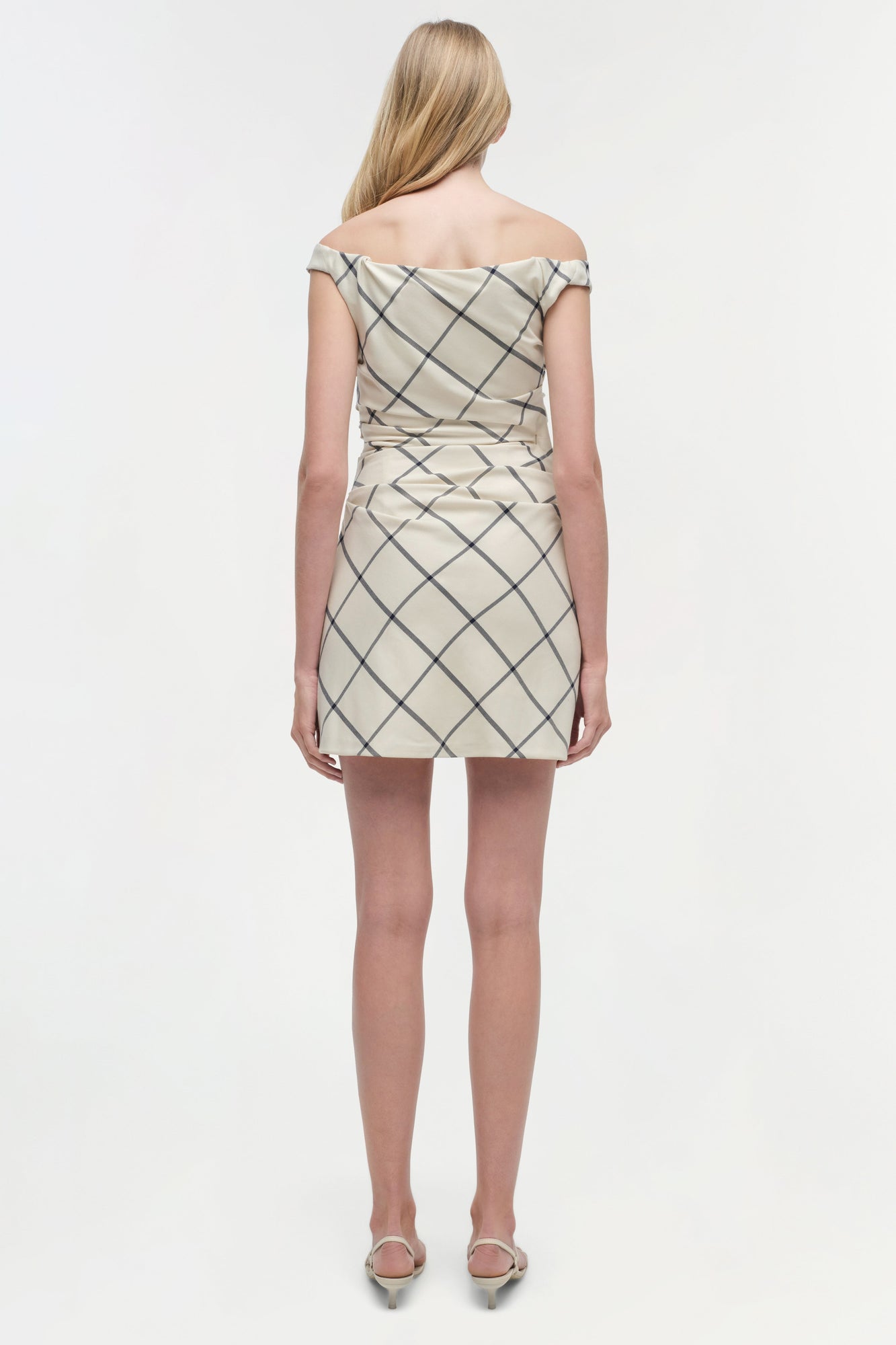 Beige mini dress with diagonal grid pattern and off-shoulder neckline, shown from back on model.