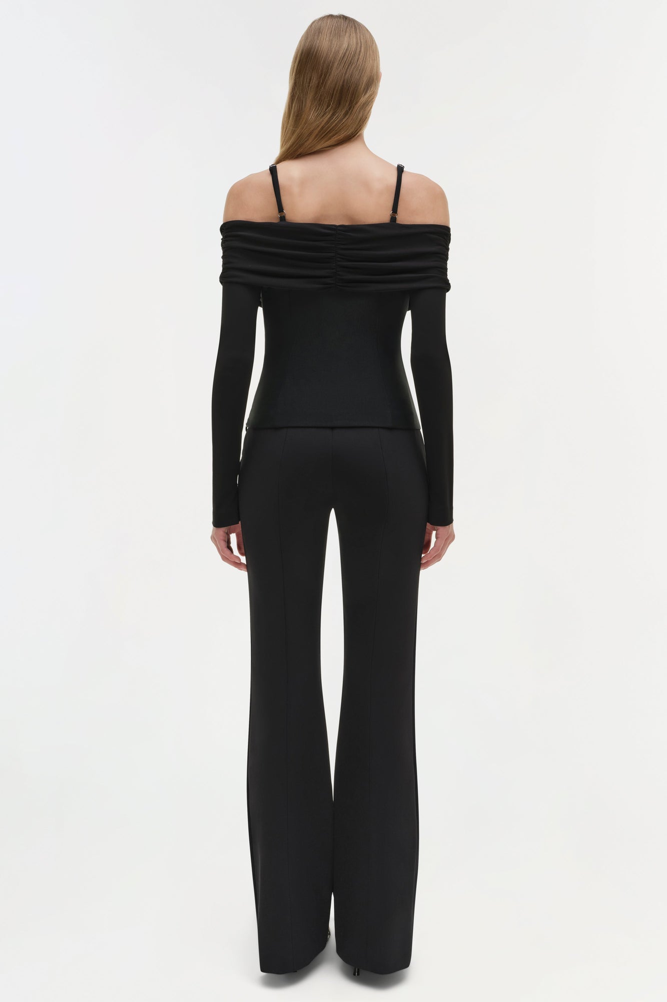 Black off-shoulder long sleeve top with ruched neckline and thin straps, shown from back view.