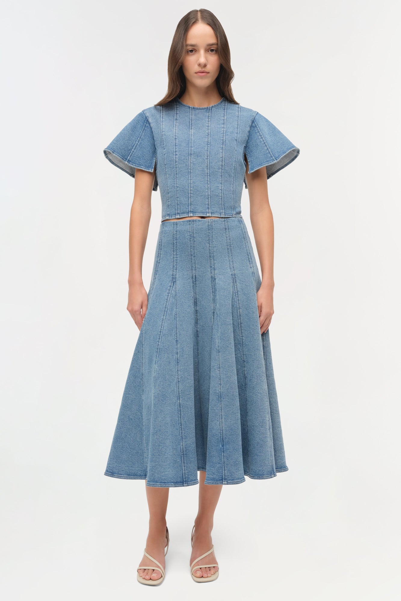Light blue denim dress with short puffed sleeves, vertical seaming detail, and A-line skirt with cutout waist.