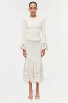 Cream knit top with long sleeves featuring lace cuffs and matching midi skirt with lace hem detail.