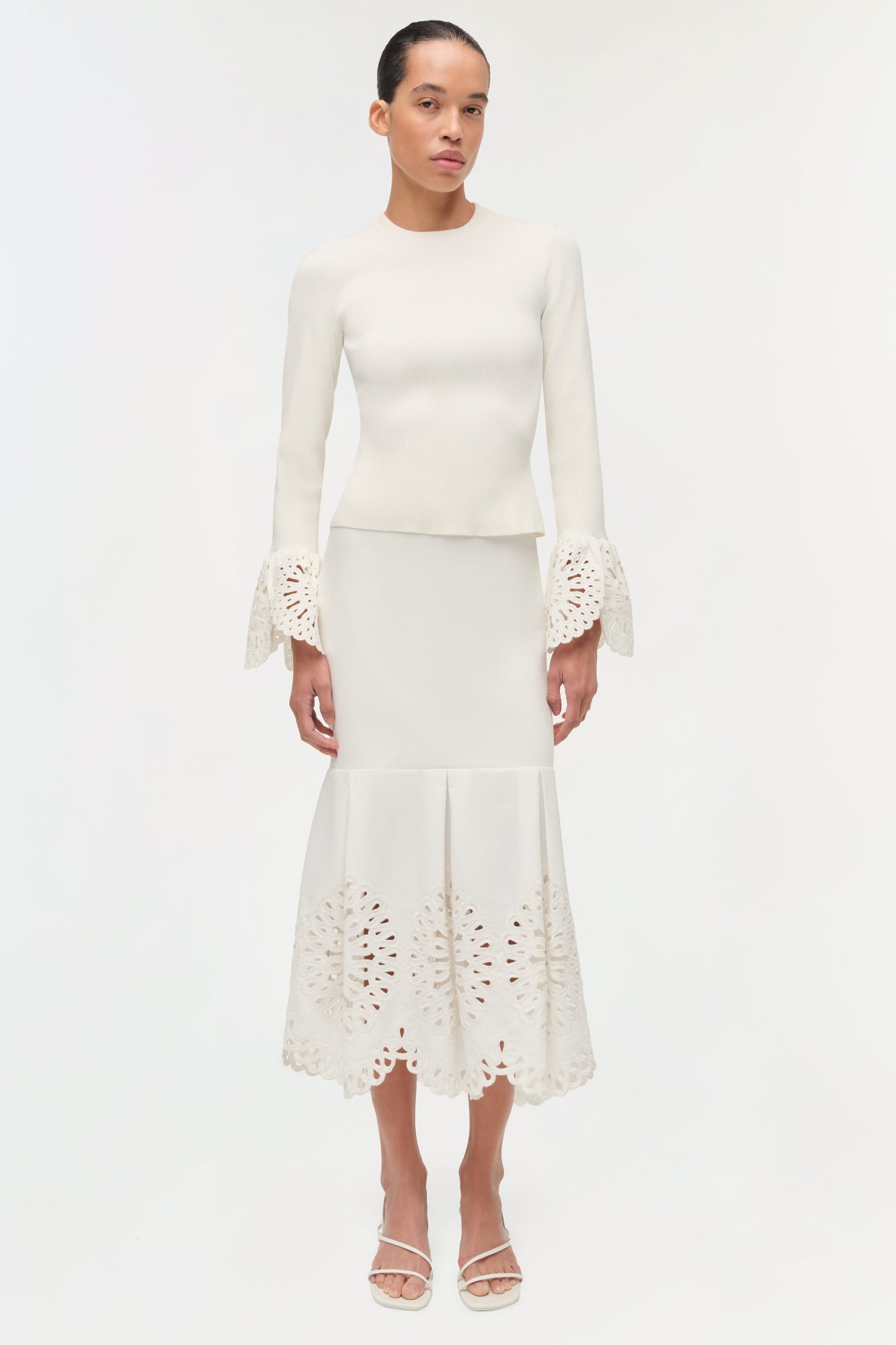 Cream knit top with long sleeves featuring lace embroidered cuffs and hem details.
