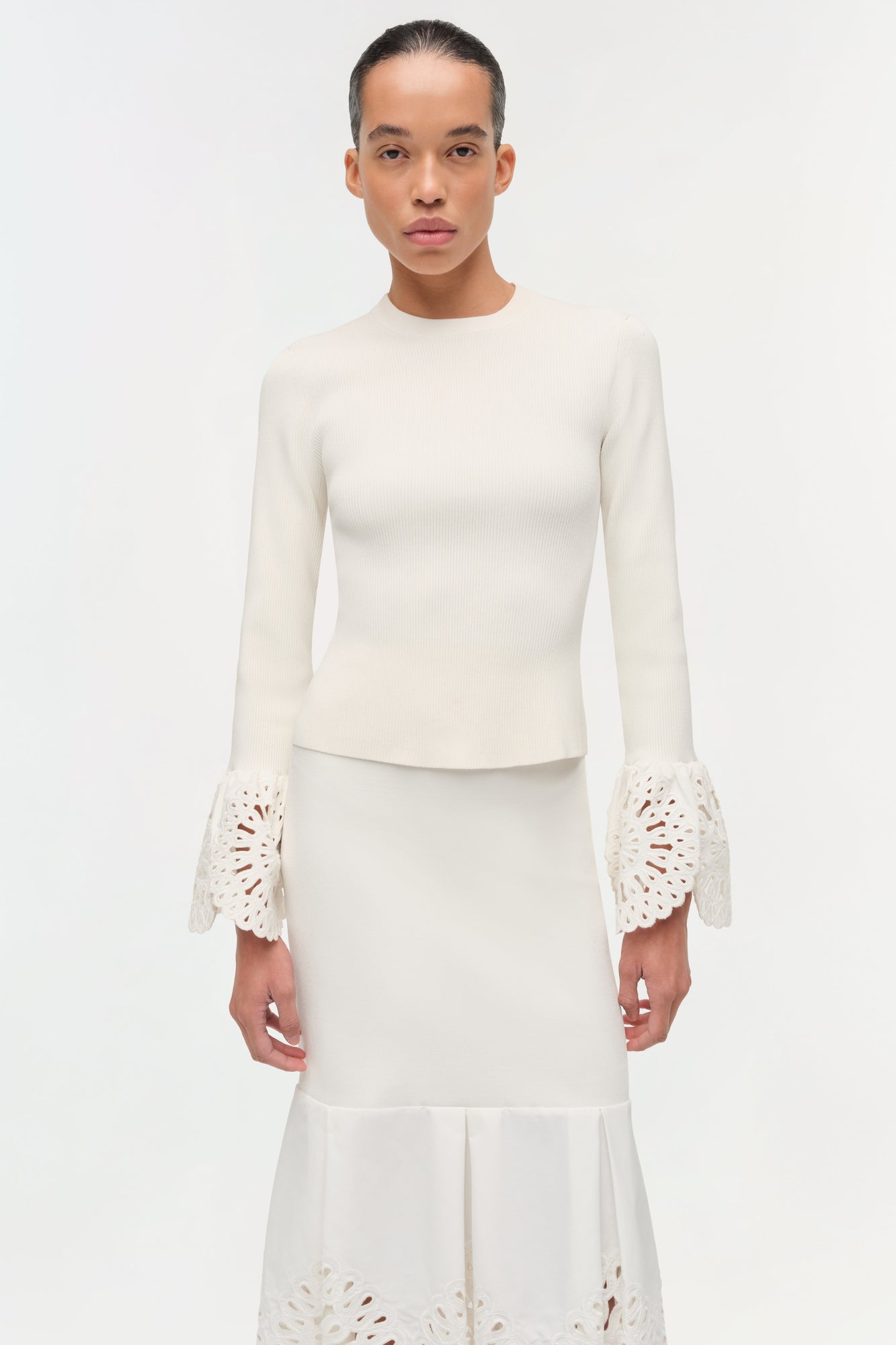 Cream ribbed knit top with eyelet embroidered cuffs and crew neckline.