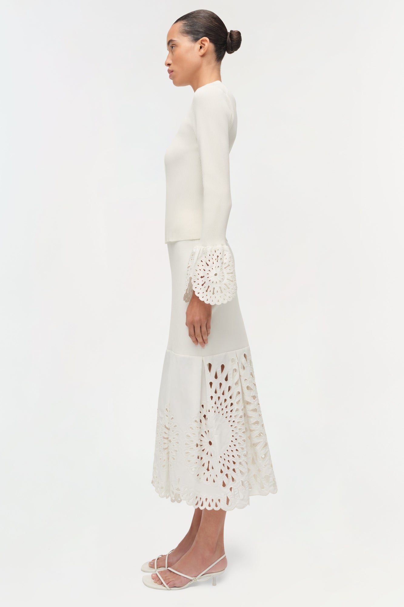Cream knit top with eyelet embroidered cuff and matching skirt with cutout details.