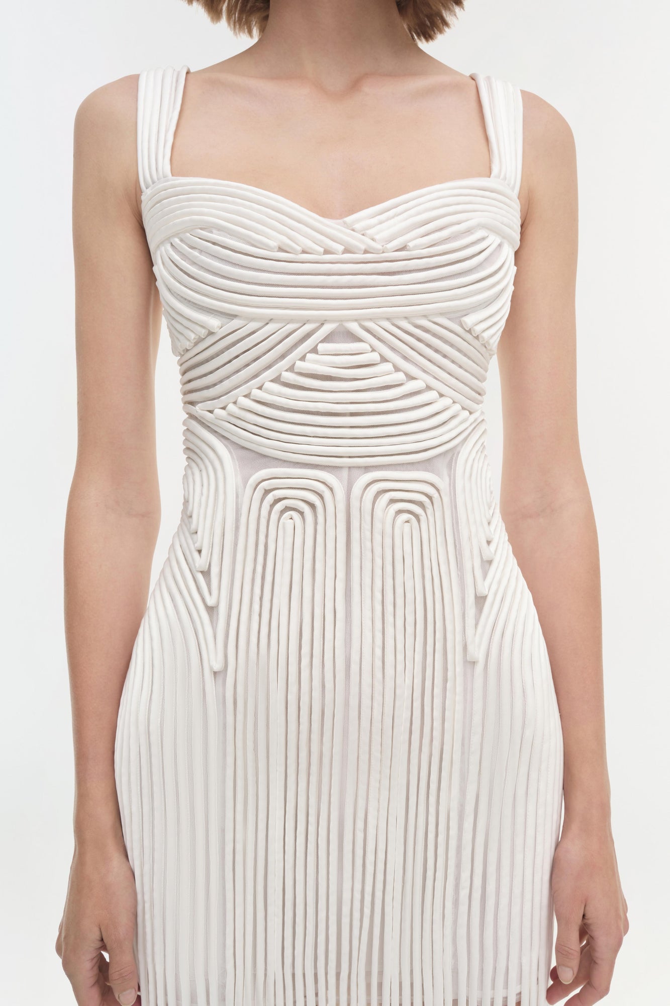White sleeveless dress with sweetheart neckline and draped pleated detailing across the bodice and skirt.