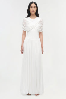 White pleated maxi dress with draped cape overlay across shoulders and short sleeves.