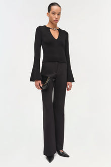 Black wool top with choker neckline and flared long sleeves on model wearing matching black trousers.