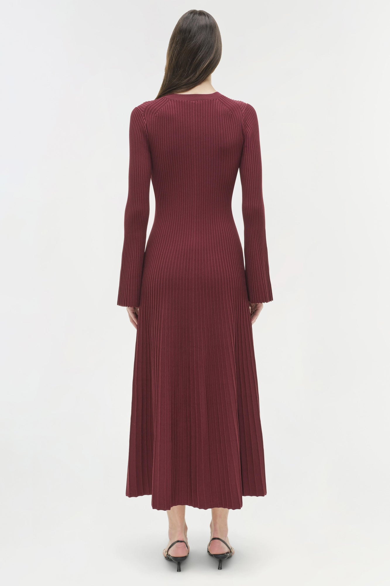 Burgundy ribbed knit midi dress with long sleeves and flared hem, shown on model from back view.