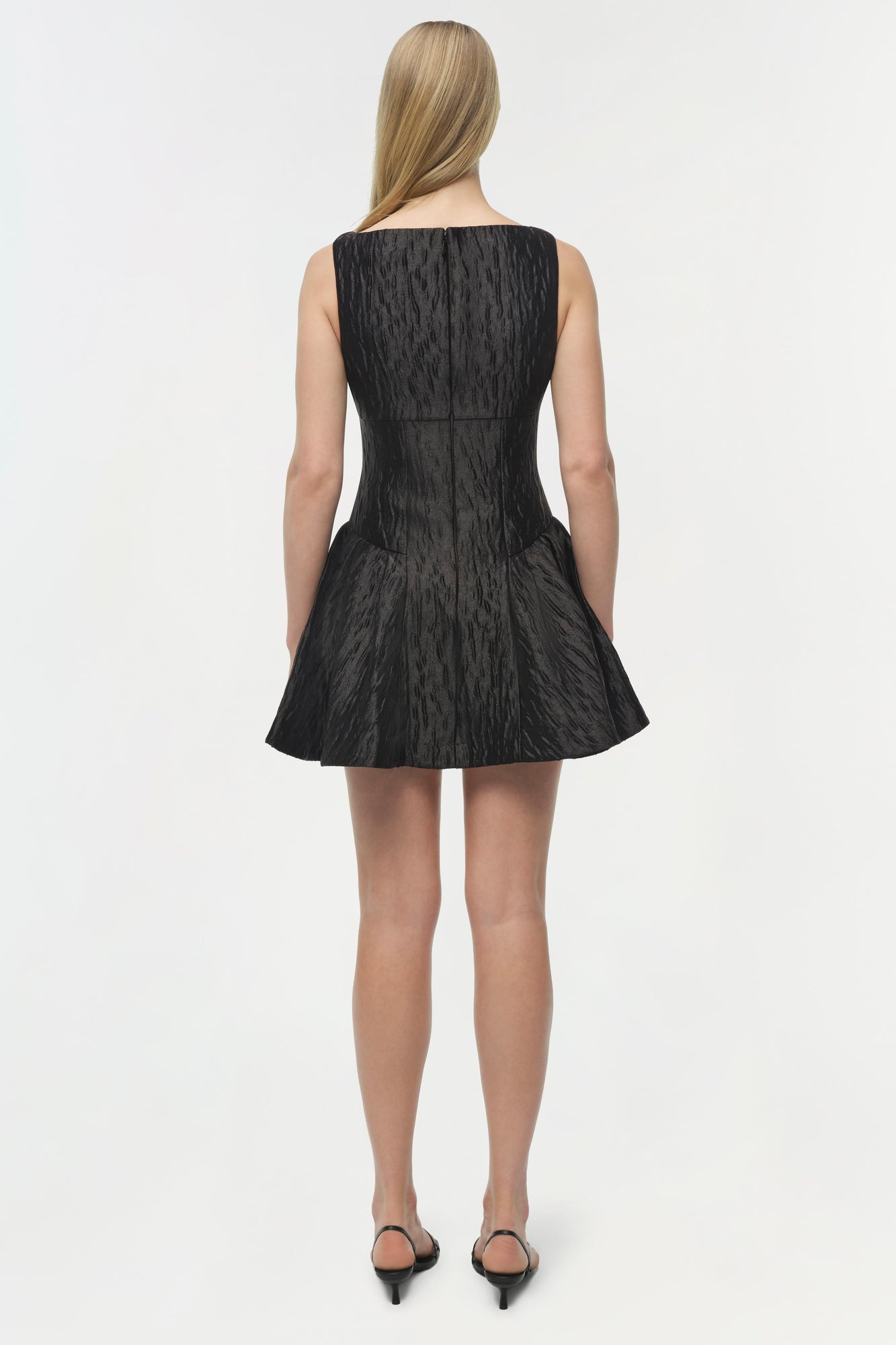 Black sleeveless mini dress with textured jacquard fabric and fitted bodice, shown from back view.
