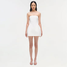 White strapless mini dress with fitted bodice and A-line skirt on model wearing strappy sandals.