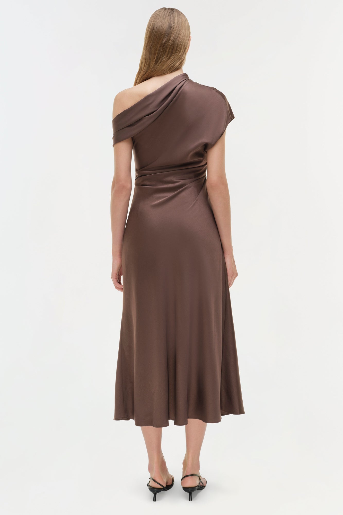 Brown satin midi dress with one-shoulder neckline and ruched waist detail, shown on model from back.