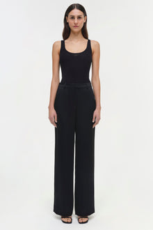 Woman wearing black Tavar pants with high waist and wide legs, paired with a black ribbed tank top.