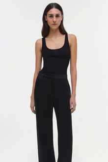 Woman wearing black Tavar pants with wide legs and high waist, paired with black ribbed tank top.