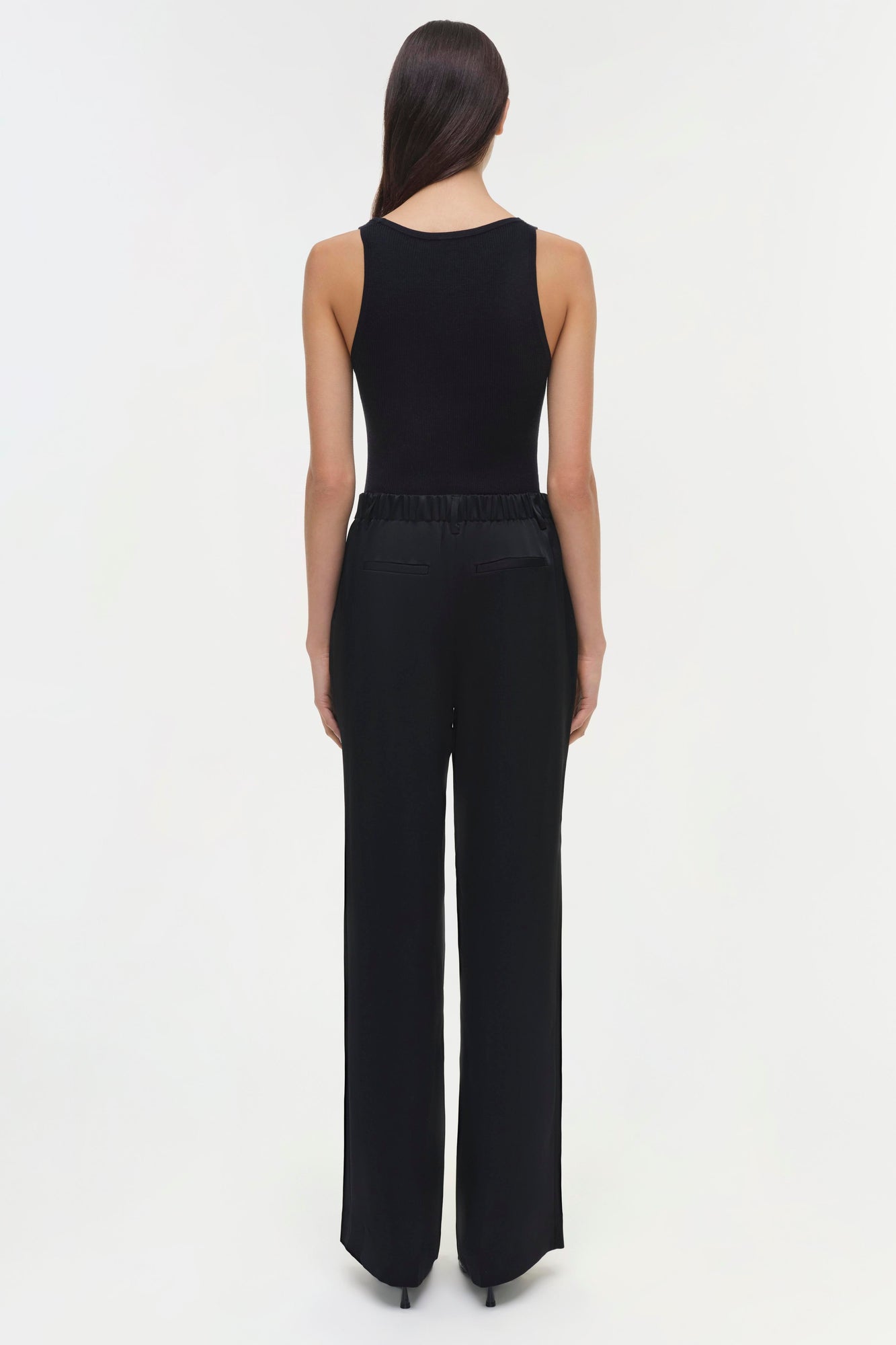 Woman wearing black Tavar pants with elastic waistband and wide-leg fit, shown from back view.