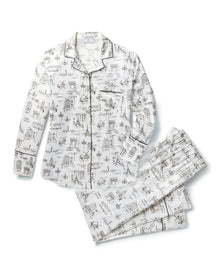 Women's Silk Pajama Set in Parisian Toile: white button-up with black piping, illustrated with buildings and trees. Includes long-sleeve top with chest pocket and matching long pants featuring an elastic waistband.