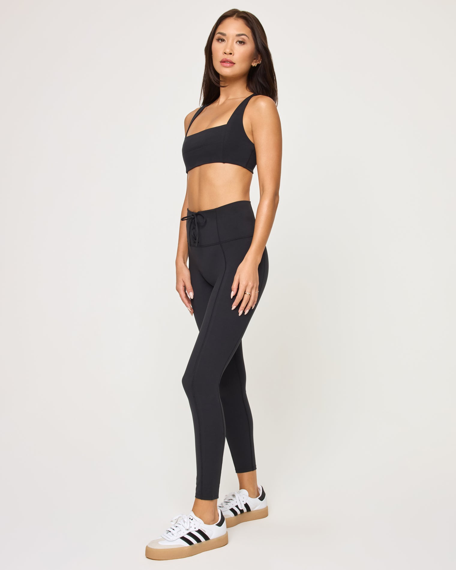 Side view of model wearing the Contender Legging in black with matching black sports bra.