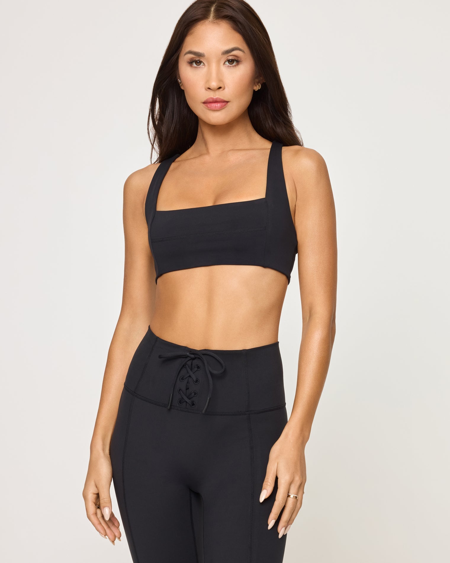 Close-up front view of model wearing the Contender Legging in black showing the high-waist and seam detail, with matching black sports bra.