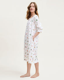 The Women's Twill Delphine Nightgown in 12 Days of Christmas is a white, long-sleeve nightgown with a gathered neckline, small bow tie, and a festive print inspired by the 12 Days of Christmas.