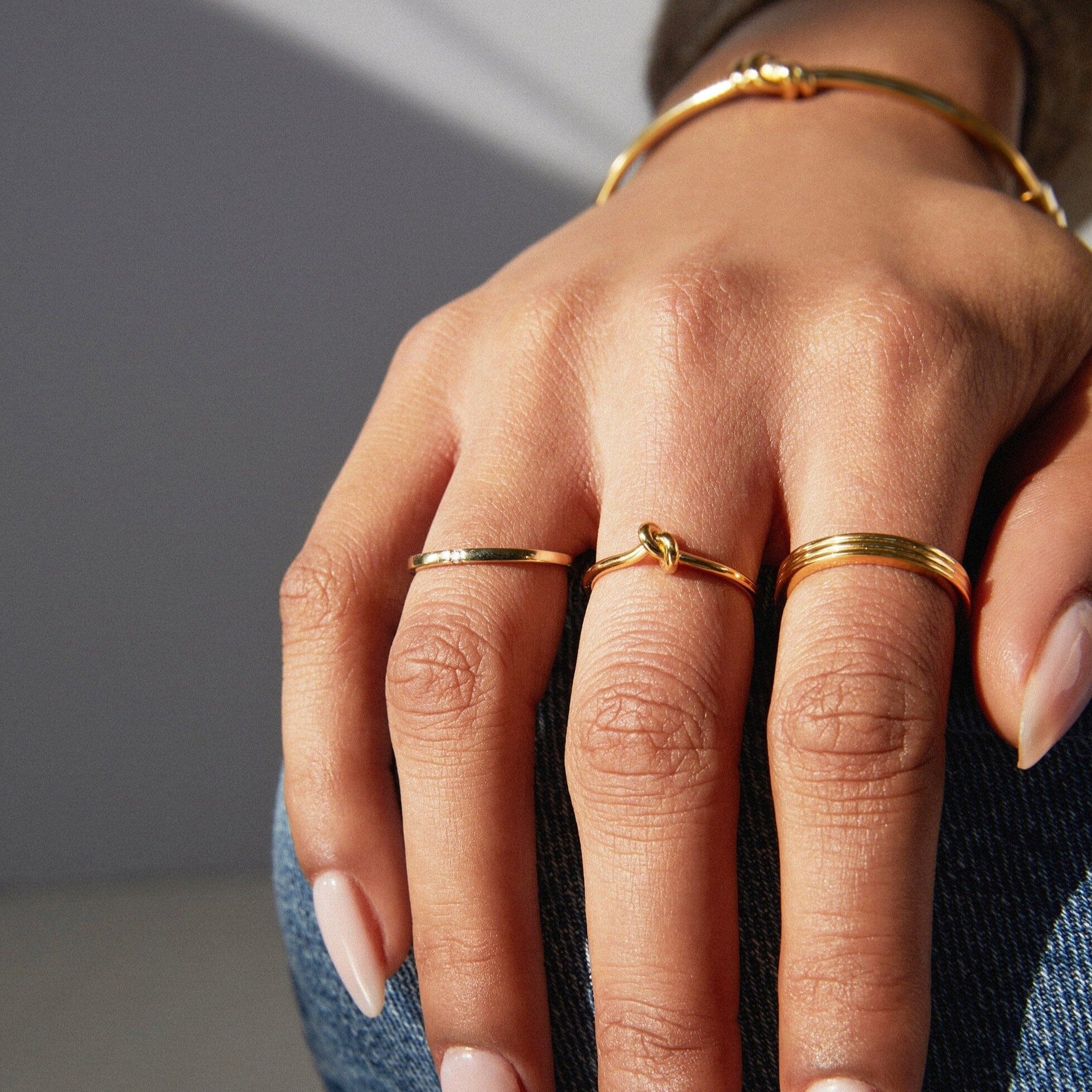 Lifestyle Model. Close up of hand wearing various gold rings.