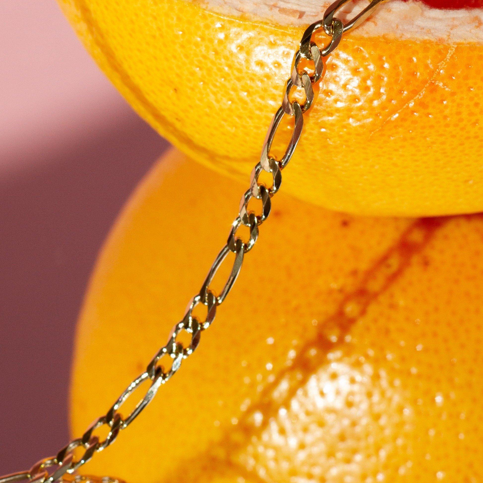 Flatlay Model. Close up of gold chain bracelet resting on lemon