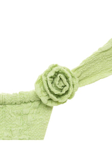 Pale green rose-shaped pin attached to a textured fabric strip with gathered edges.