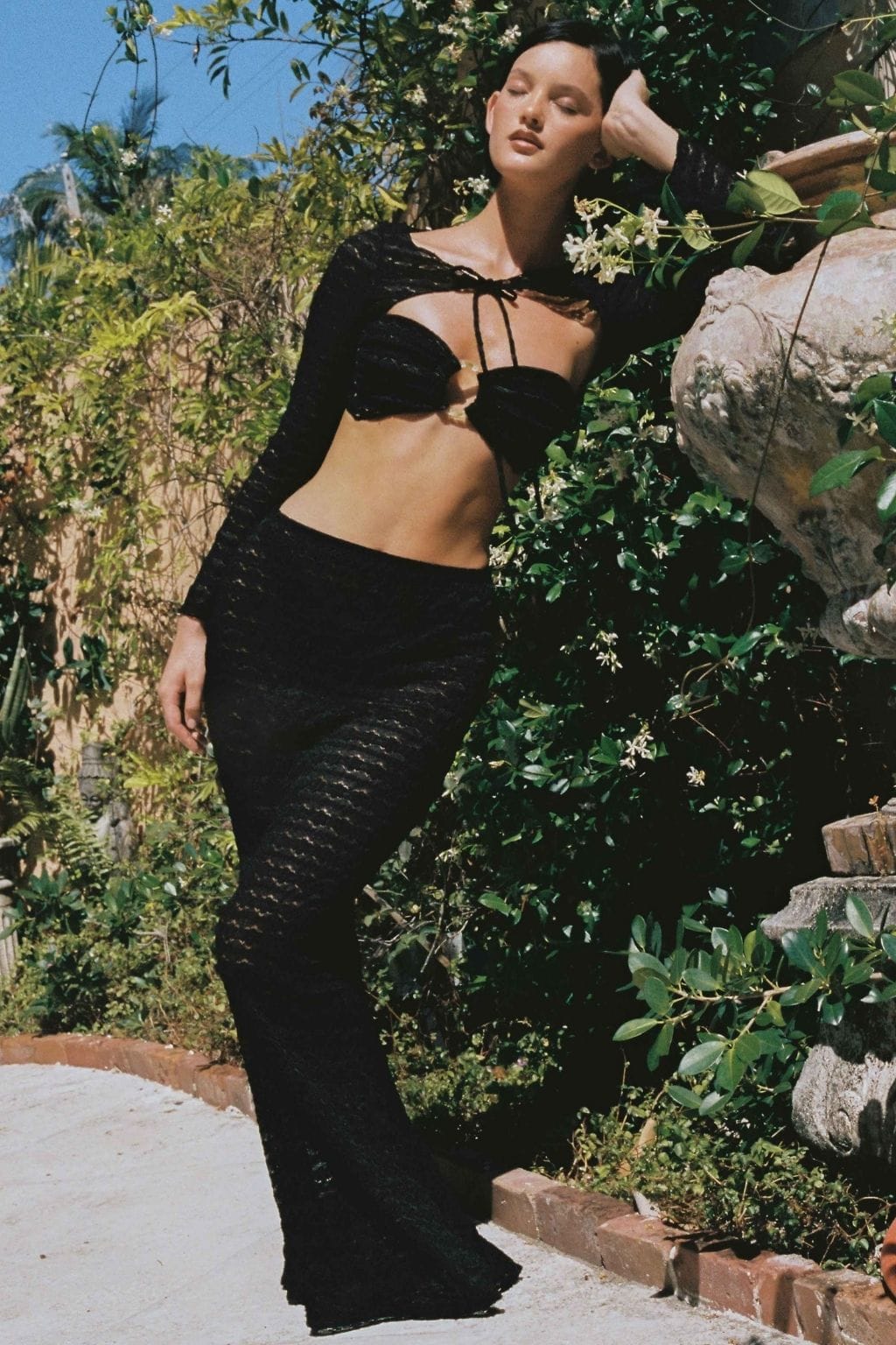 Black lace crop top with tie neckline and long sleeves, worn as part of a two-piece set.
